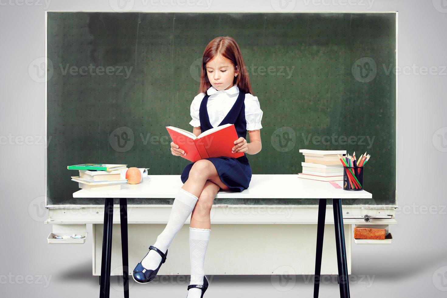 linda jovencita sentada en la mesa y leyendo un libro foto