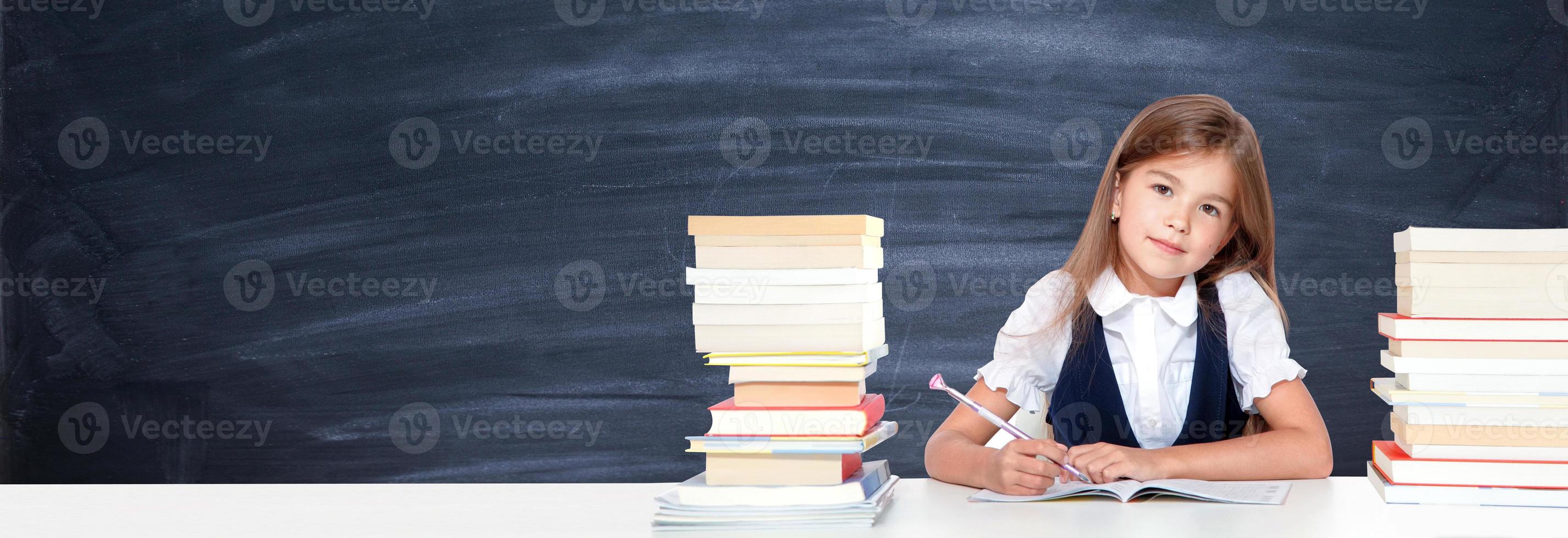 feliz y linda colegiala adolescente escribe en un libro o cuaderno foto