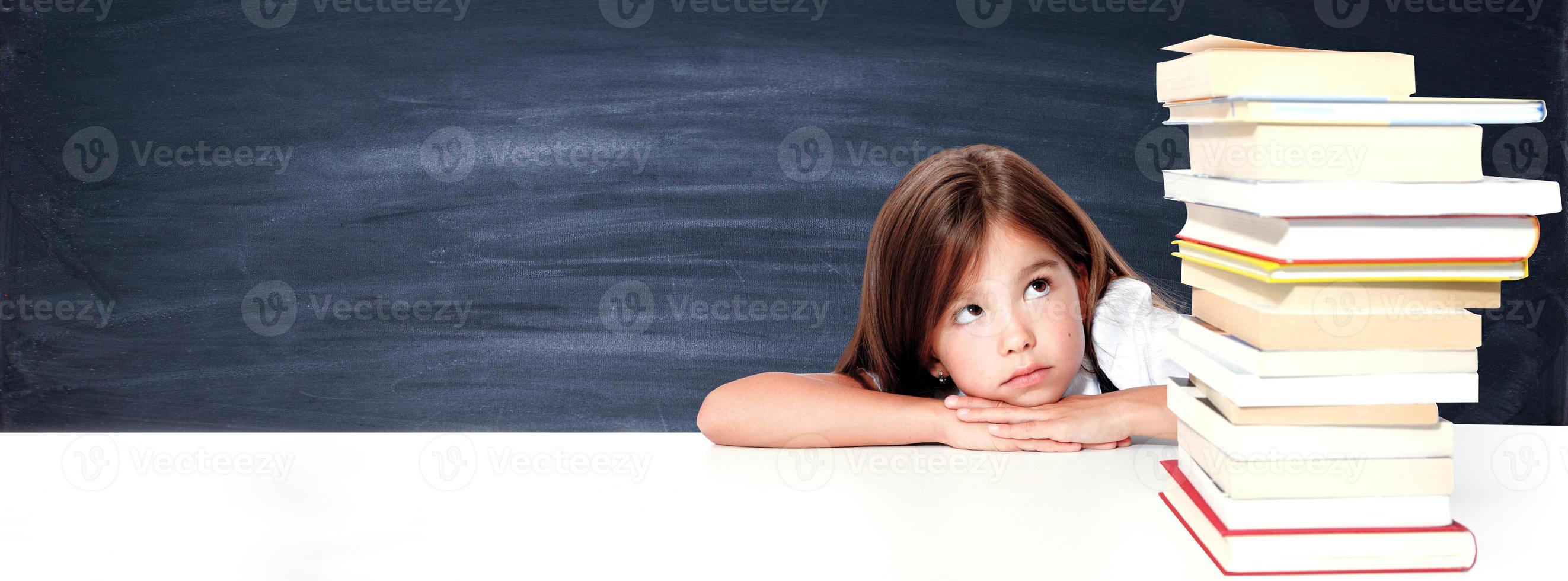 Young cute girl sitting at the table and reading a book photo