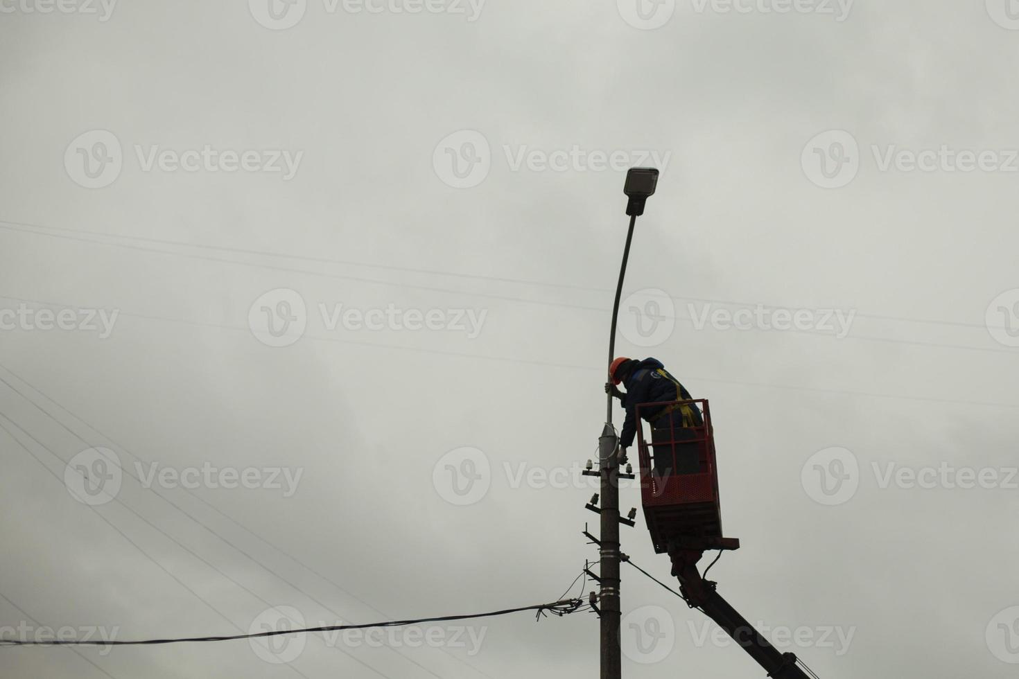 The high-riser changes the wires. Work at height. Repair of a pole with a lamp. photo