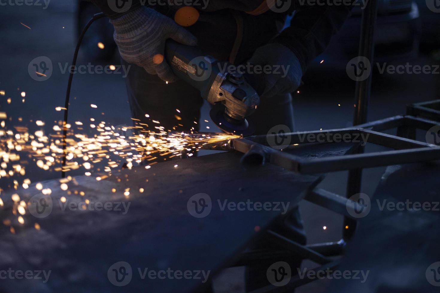 Sparks from grinding metal. Steel processing in workshop. Lights in dark. Production of parts. Cutting became grinder. photo