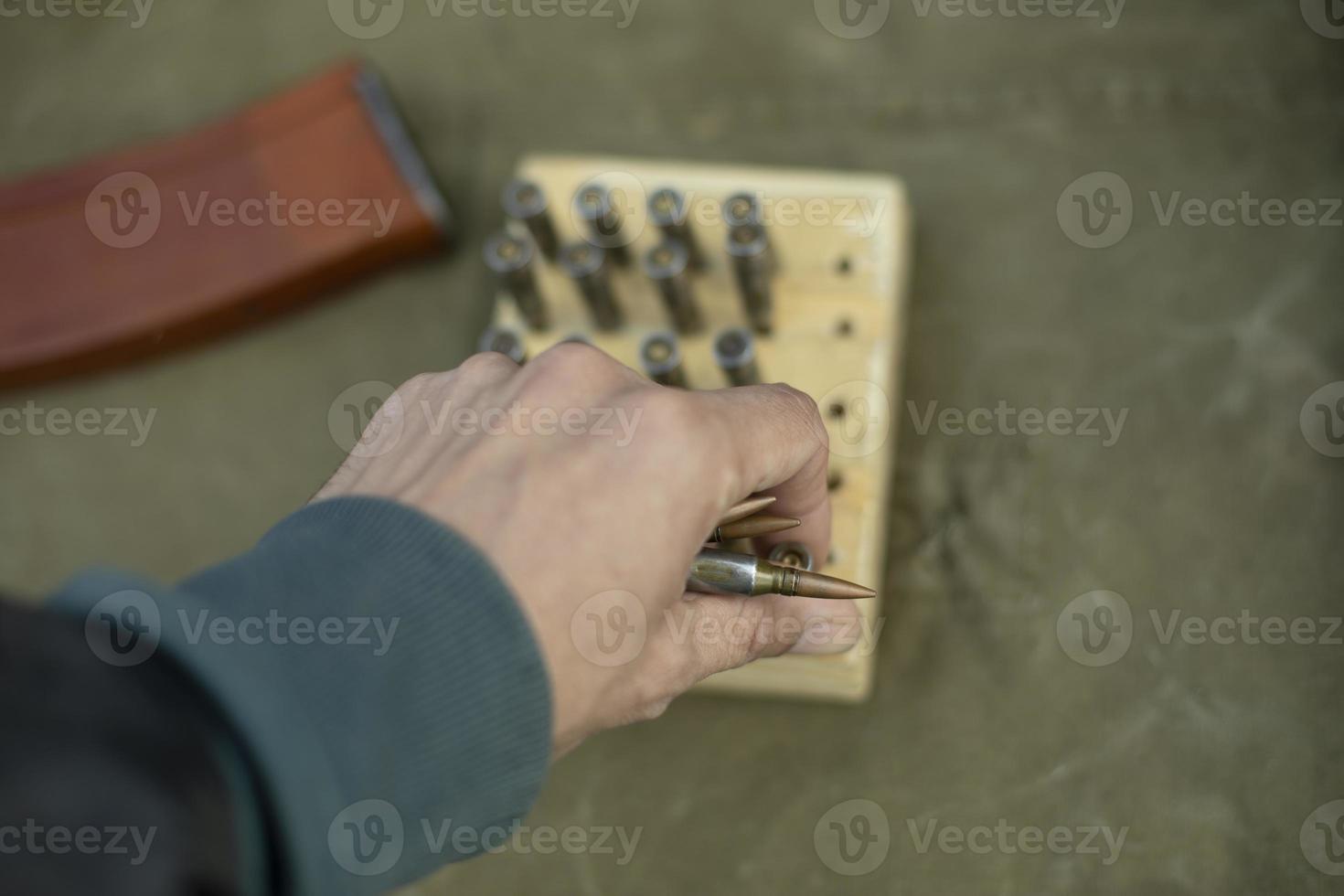 The hand takes the ammo. Cartridges from automatic firearms. photo