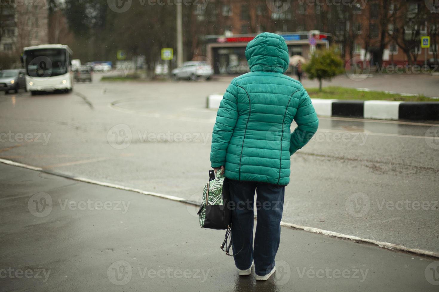 A woman looks at the road. A woman in Russia at a bus stop. Waiting for transport. photo