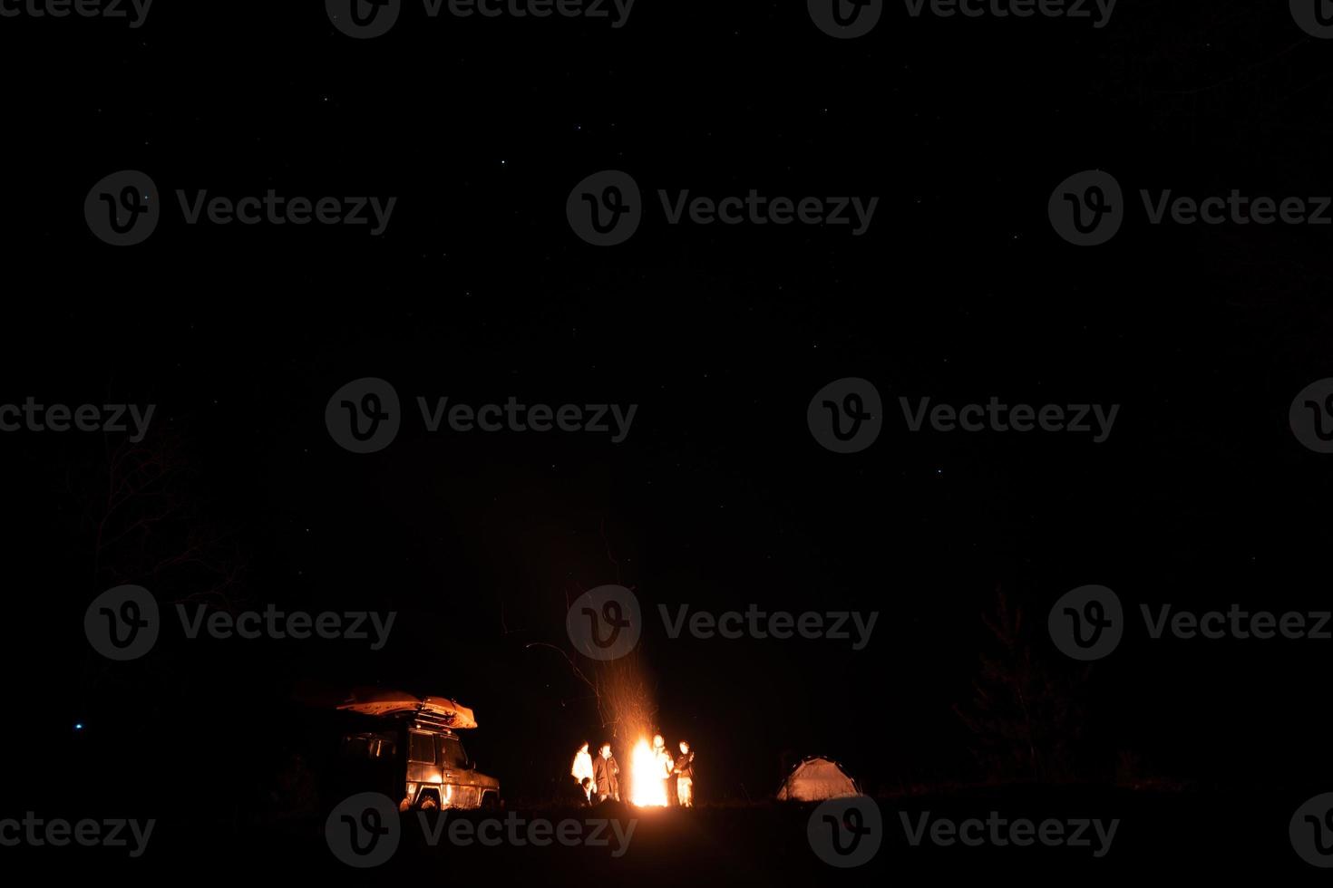 Happy Friends having a rest together around campfire photo