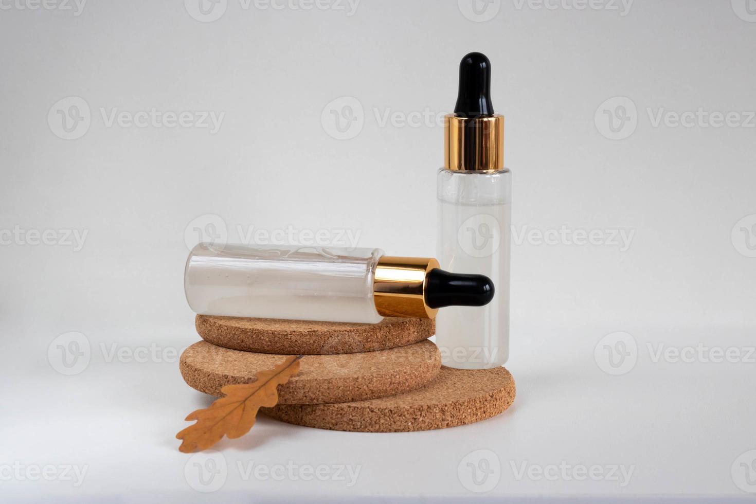 dos botellas heladas con una pipeta, aisladas en soportes de corcho sobre un fondo blanco. el diseño es adecuado para el diseño de cosméticos. foto