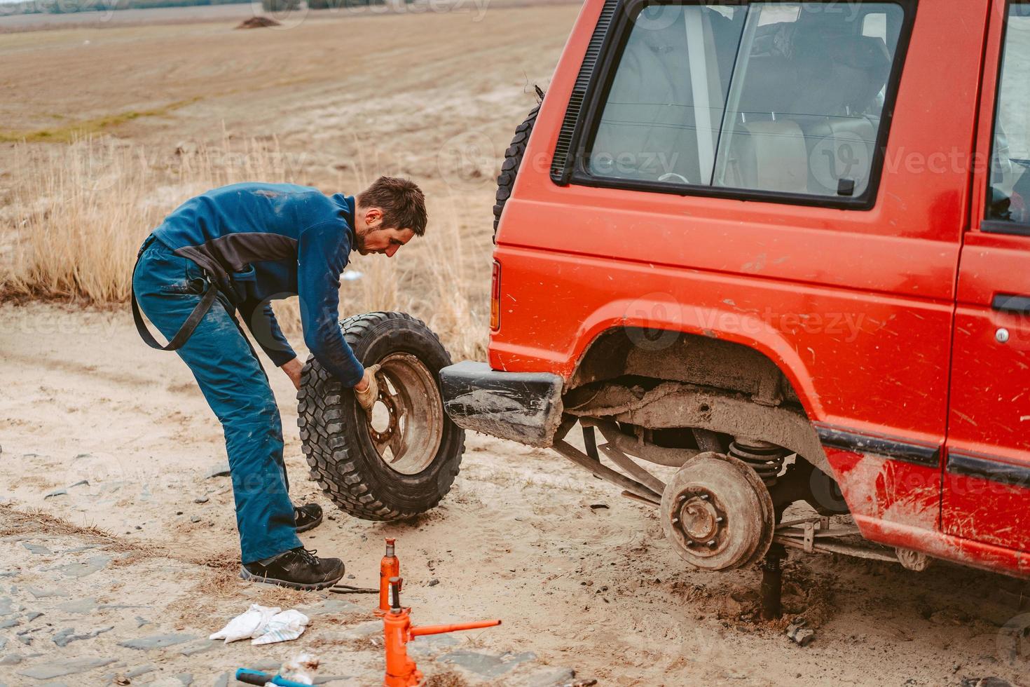 el hombre cambia la rueda manualmente en un camión todoterreno 4x4 foto