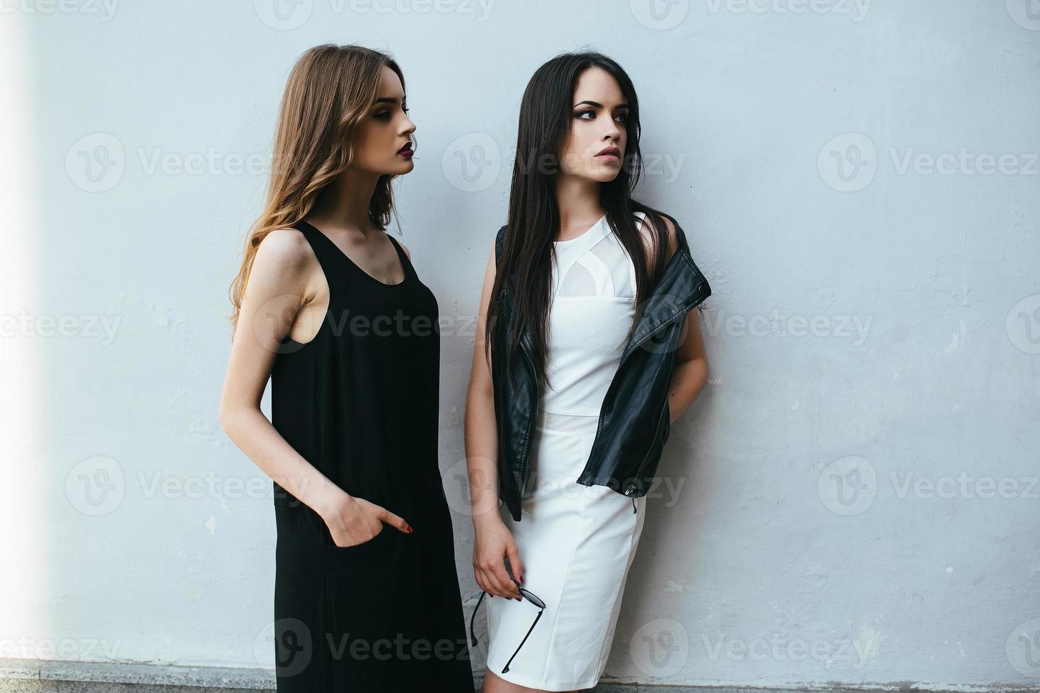 Two beautiful friends pose on white background photo