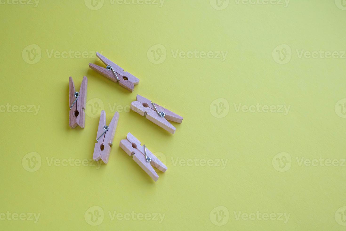 Set of small wooden clothespins for decoration on a yellow background photo