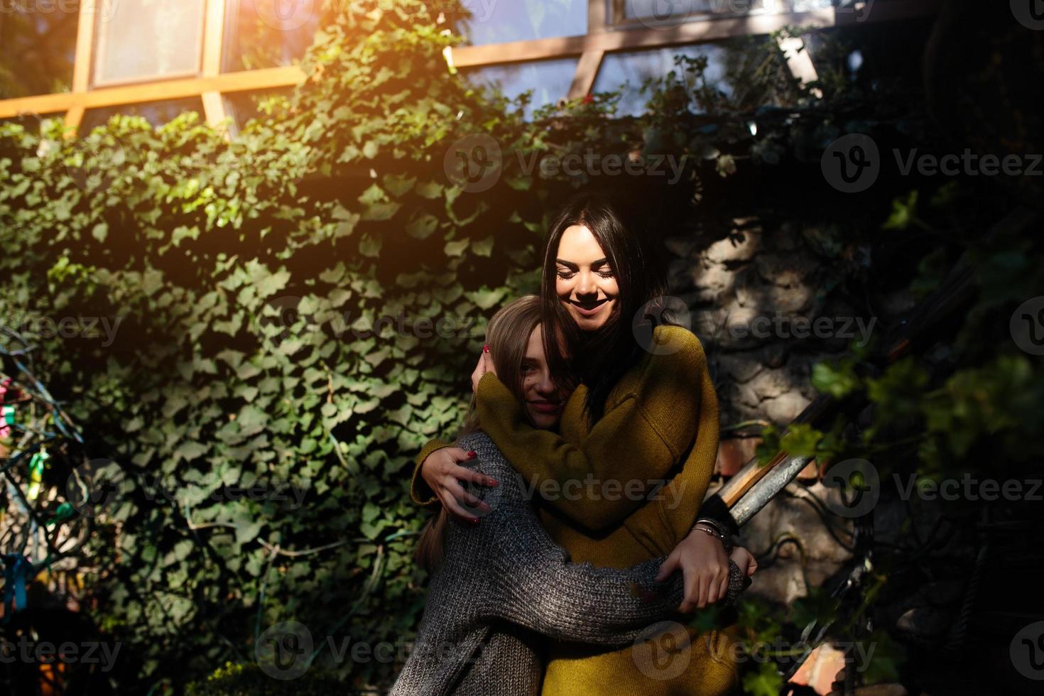 Two girls hugging in the shade of of leaves photo