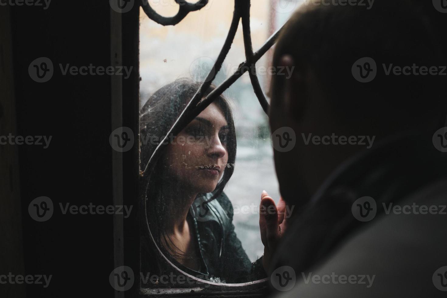 pareja joven europea mirándose a través de la ventana foto