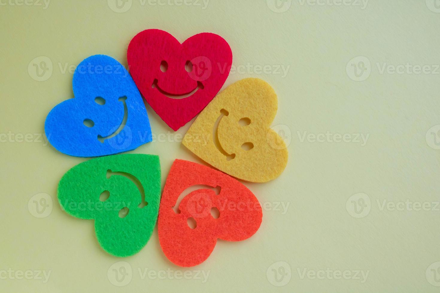 A flower made of felt multicolored hearts. Valentine's day background with beautiful toy hearts isolated on yellow background. . Bright hearts with smiles on a yellow background. Copy space. photo