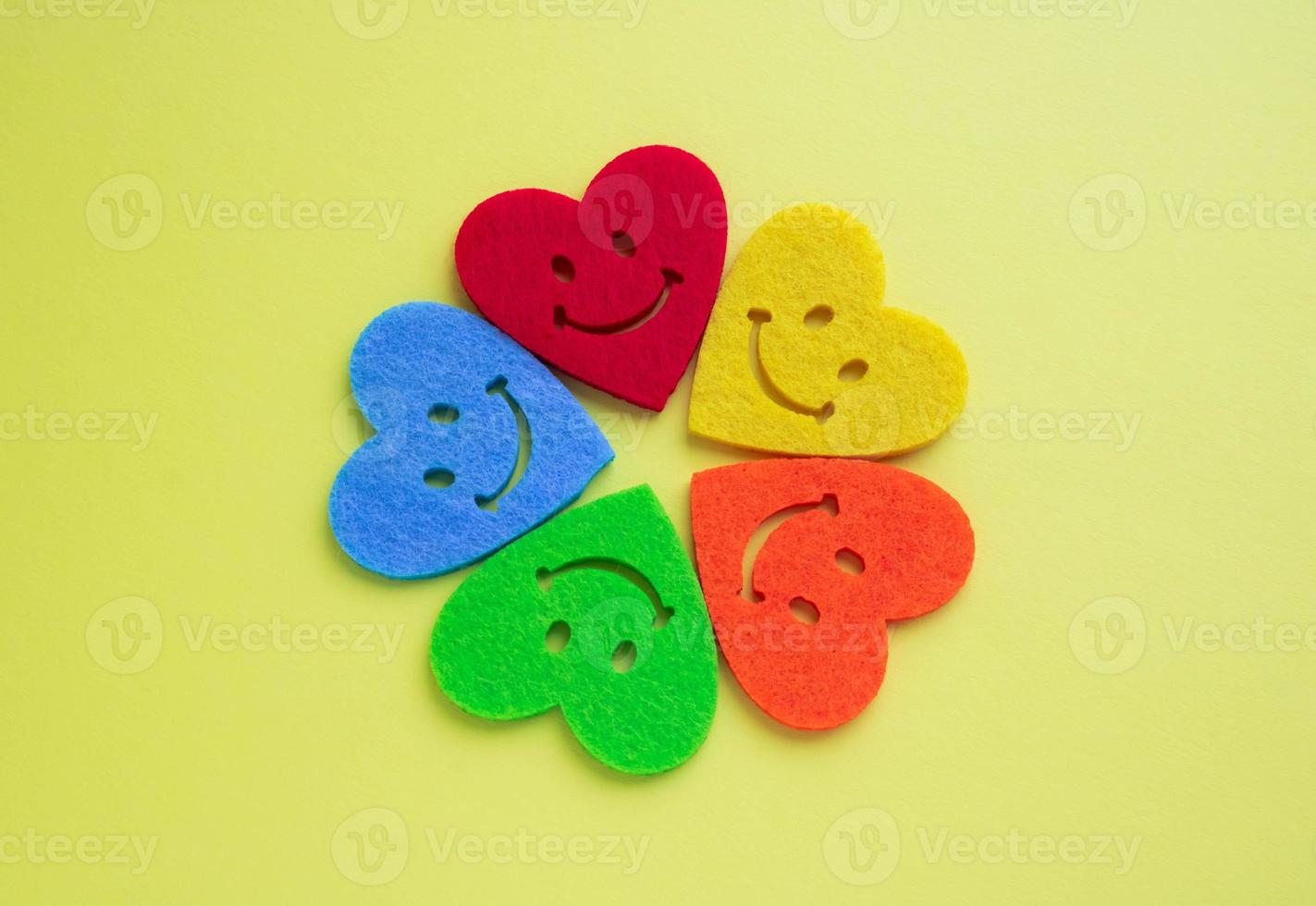 Valentine's day background with beautiful handmade toy hearts isolated on yellow background. Love is a romantic concept. Bright hearts with smiles on a yellow background. Copy space photo