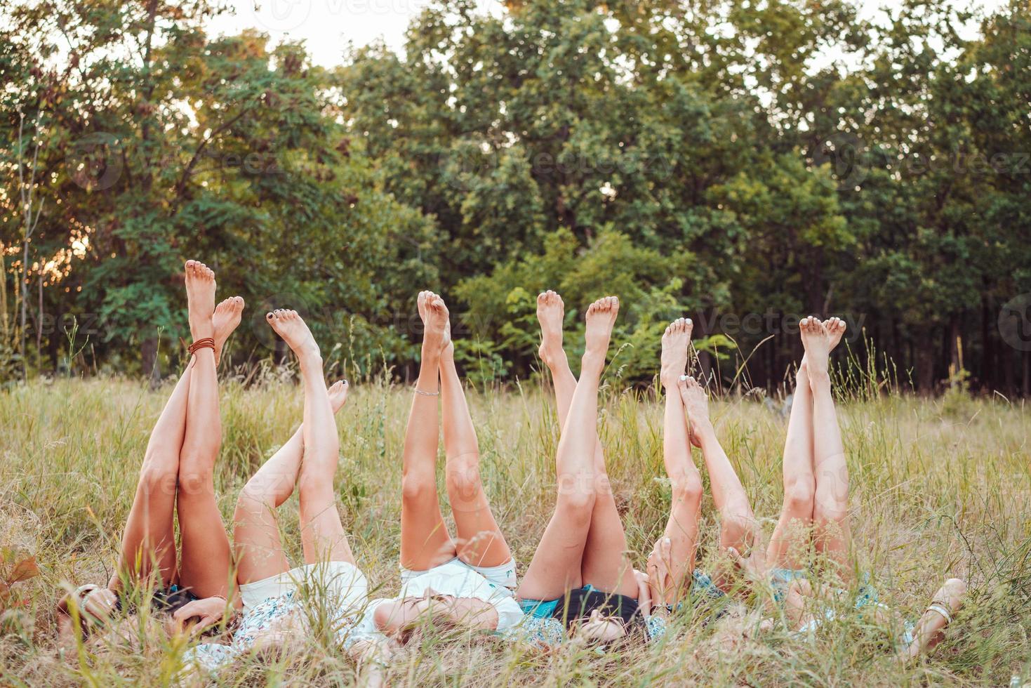 Six girls lie on the grass and raise their legs up photo