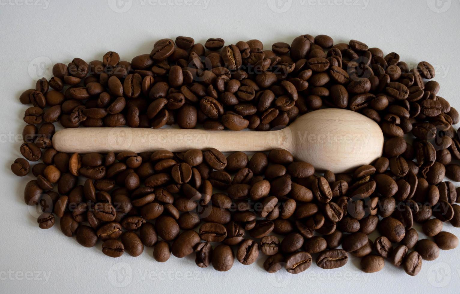 granos de café aromáticos en una cuchara de madera, para la producción de un delicioso café. granos de café tostados enteros para moler foto