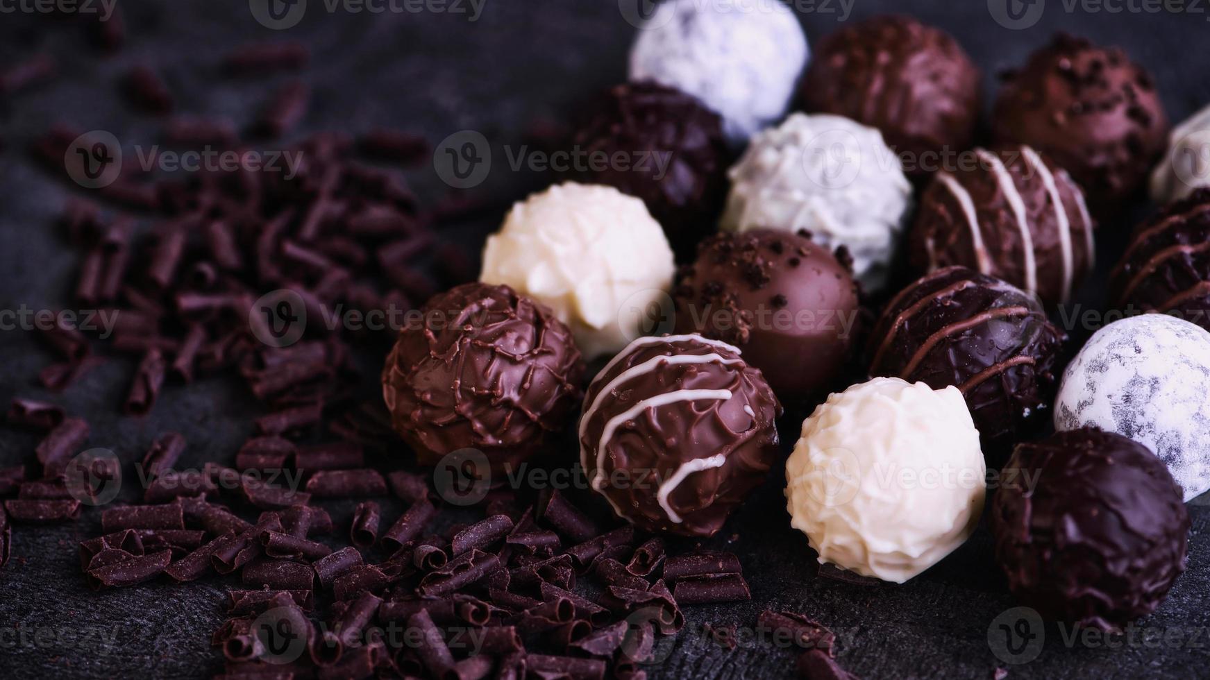 dieciséis trufas de chocolate junto a unas hojuelas de chocolate foto