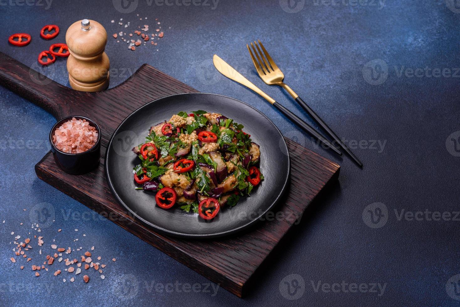 una ensalada de berenjena al horno, pimiento dulce, ajo, calabacín y perejil en un plato negro foto