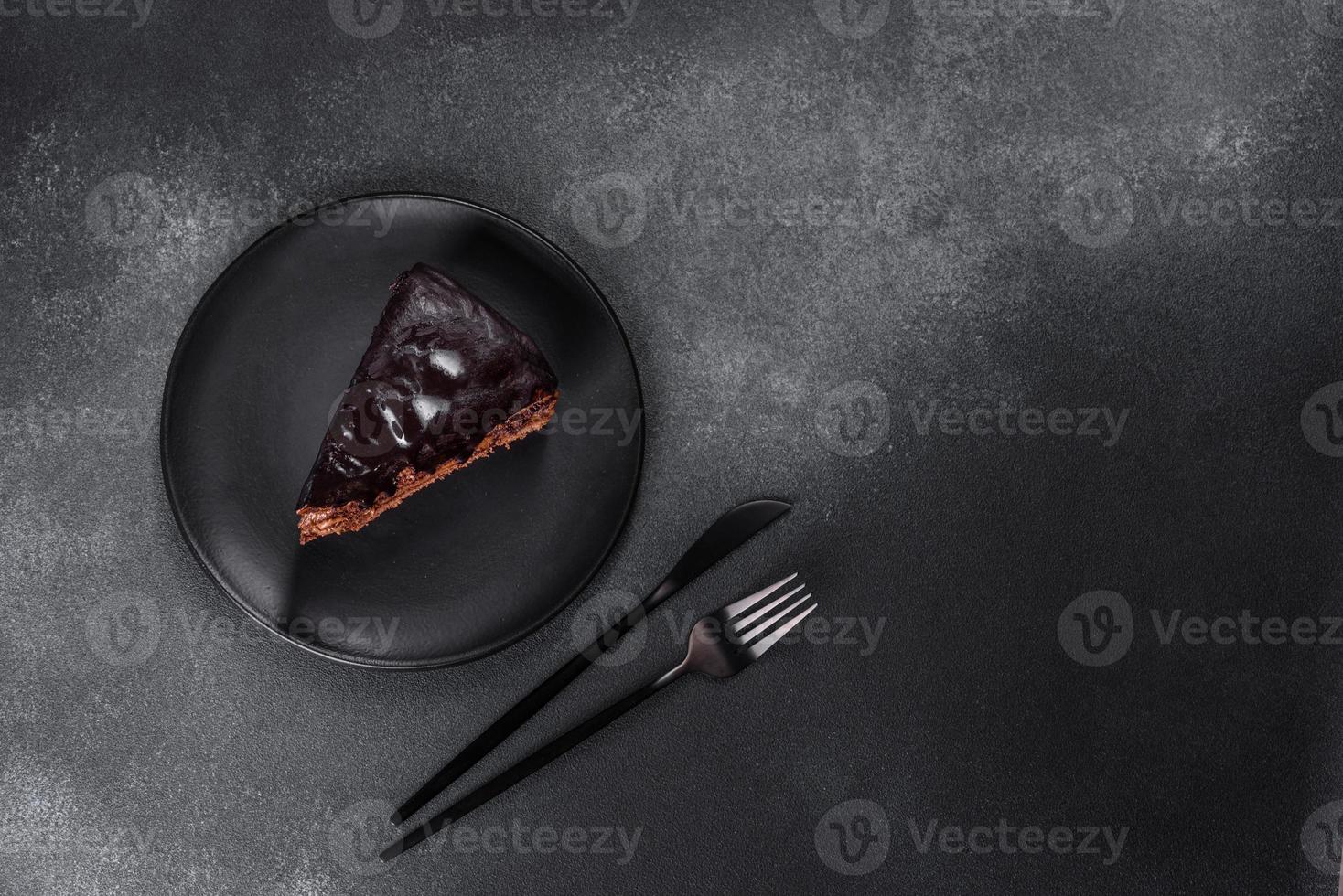 A piece of fresh delicious cake with nuts and chocolate on a black plate photo