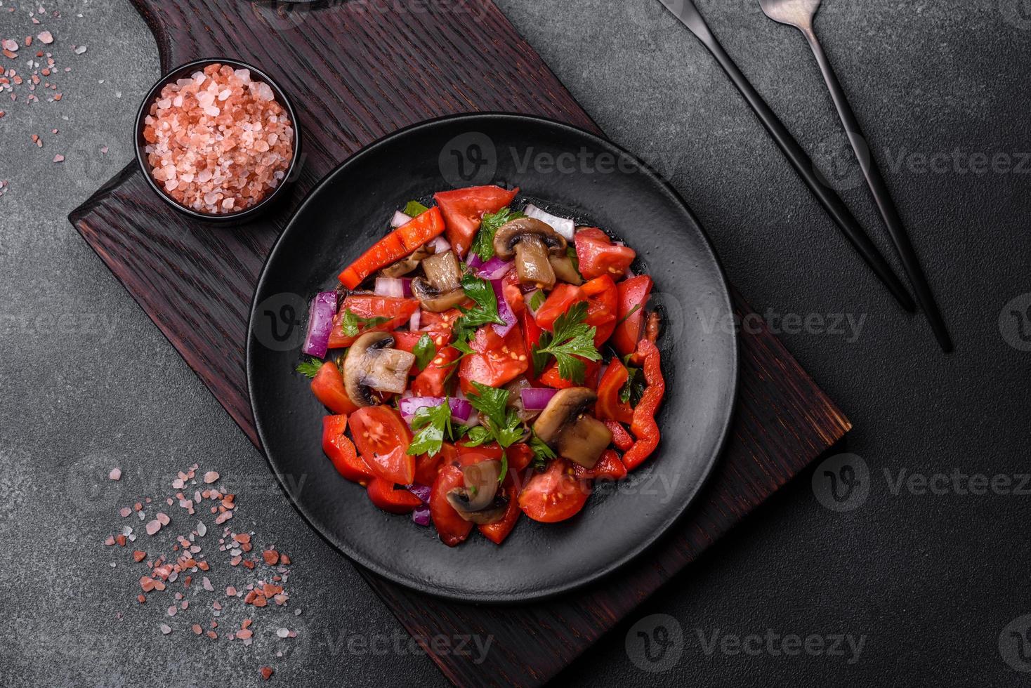 A salad of baked mushrooms, tomatoes, onions, parsley, spices and herbs photo