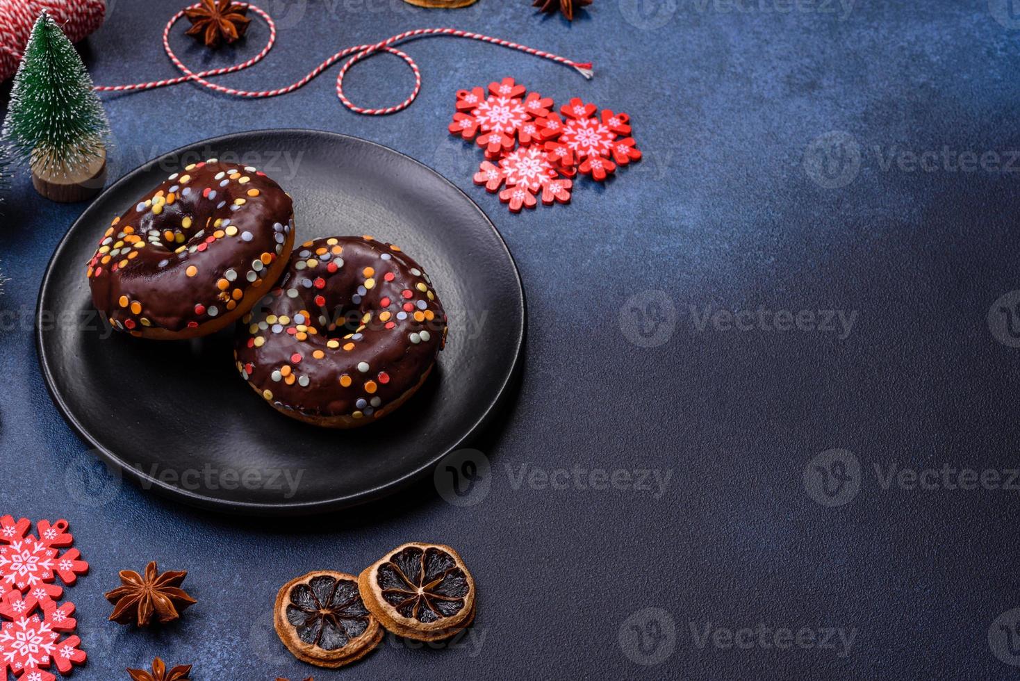 concepto de pasteles. donuts con glaseado de chocolate con chispas, sobre una mesa de hormigón oscuro foto