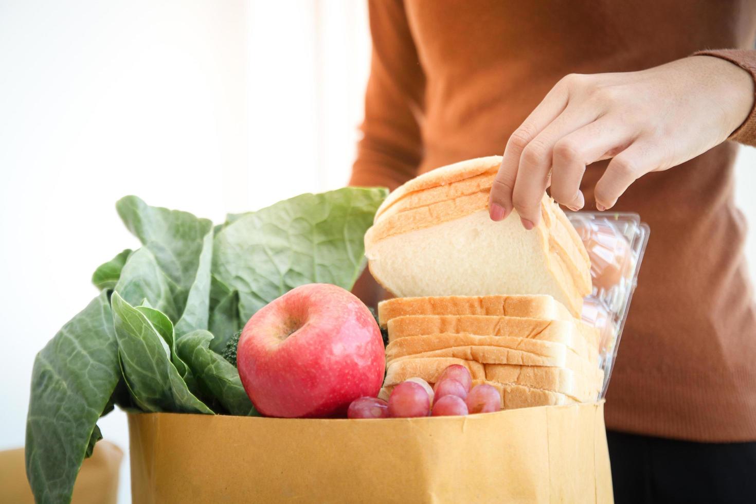 Beautiful hand woman Grab the bread from the brown paper bag. Order from the grocery store online for home delivery. photo