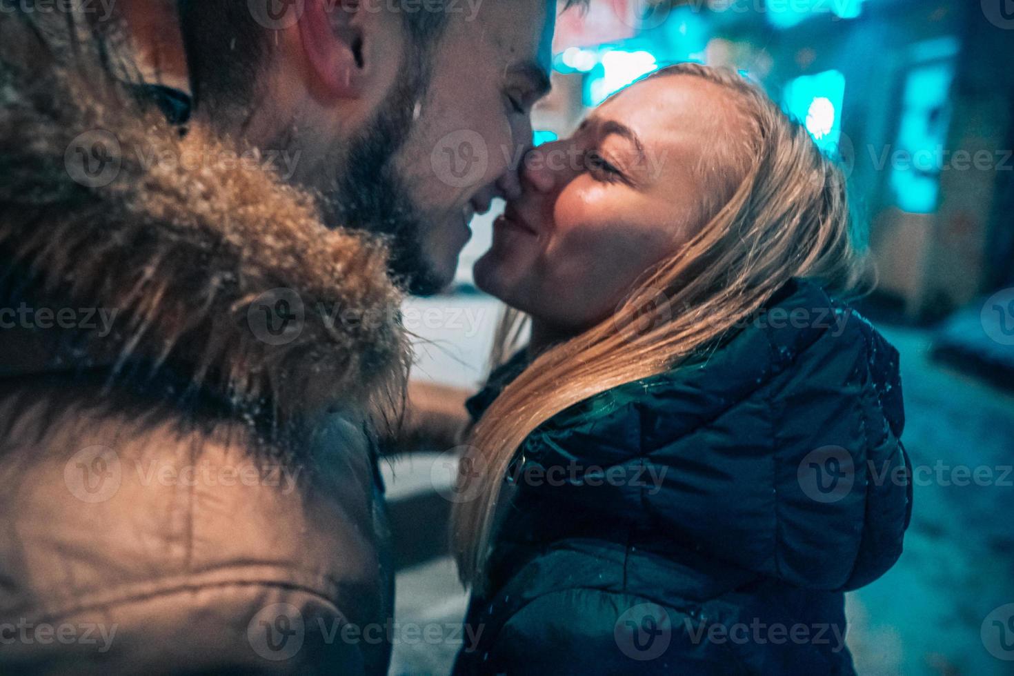 Adulto joven pareja besándose en la calle cubierta de nieve foto