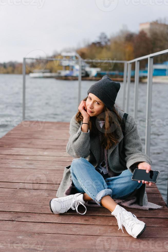 chica guapa joven en un banco de madera en el viejo muelle foto