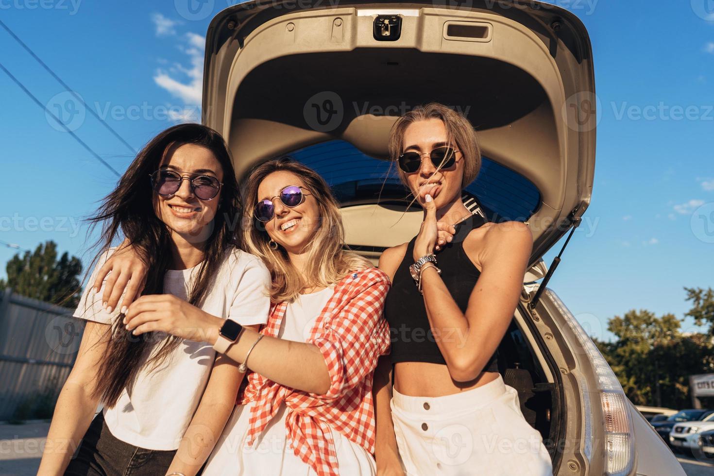 Three young woman posing for the camera the car park. photo