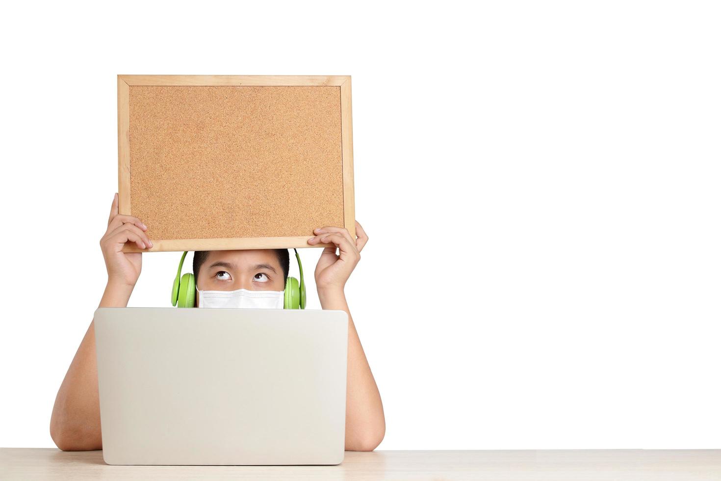 Asian boys learn online from home through video calls, using their laptop computers to communicate with their teachers. Hold a wooden sign for writing messages. Education concept Social distance. photo