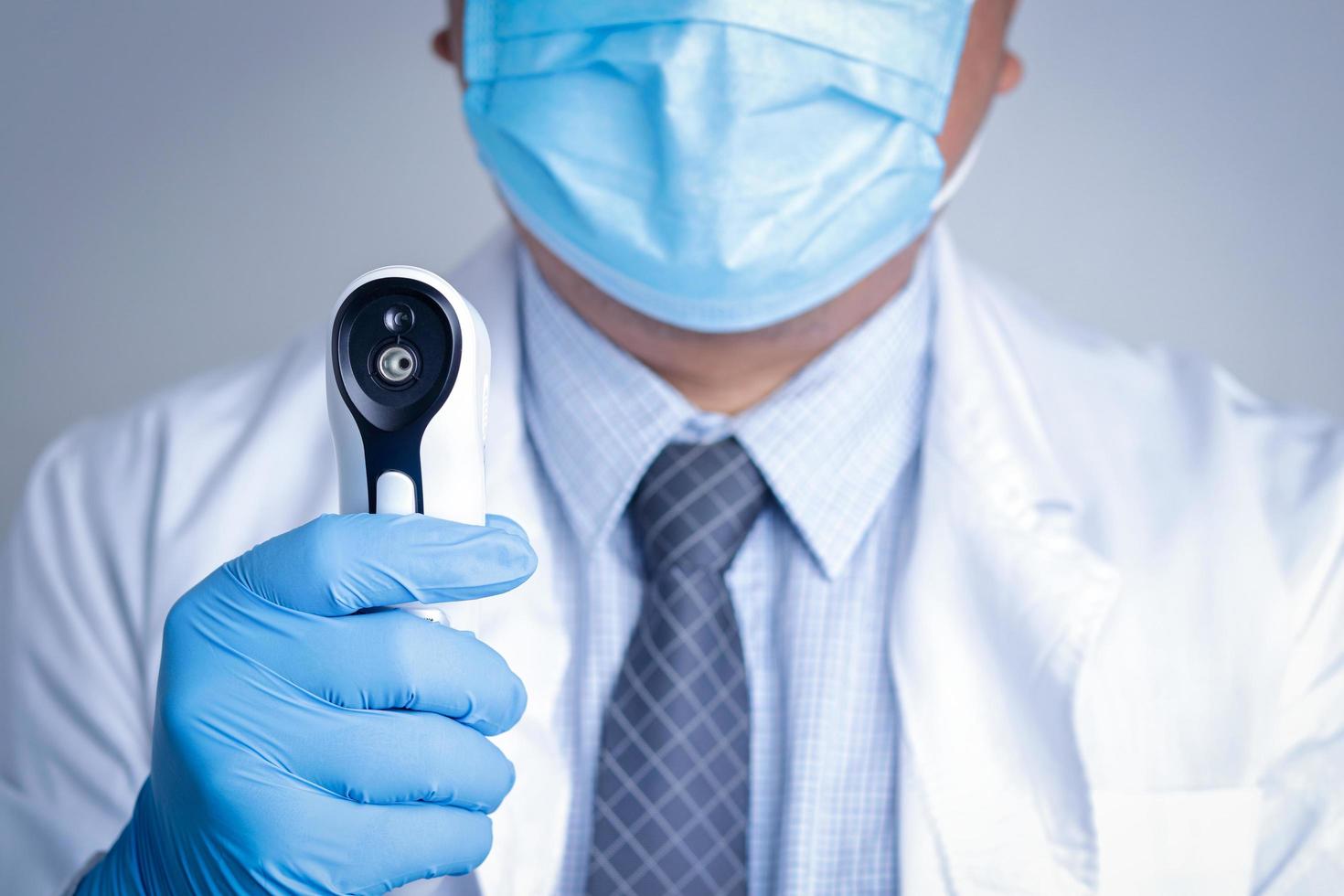 Doctors wearing masks and blue gloves. Hold the digital thermometer to monitor the patient. Medical service concept Coronavirus treatment. Copy space photo