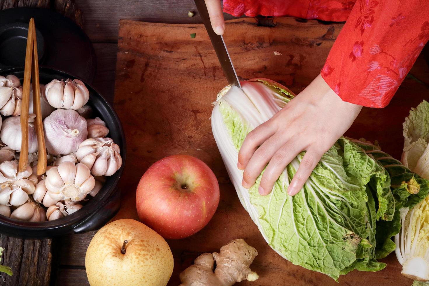 Korean women wear traditional red hanboks, make kimchi by slicing Chinese cabbage. The concept of cooking fermented, charming and fragrant, Asian food from folk wisdom photo