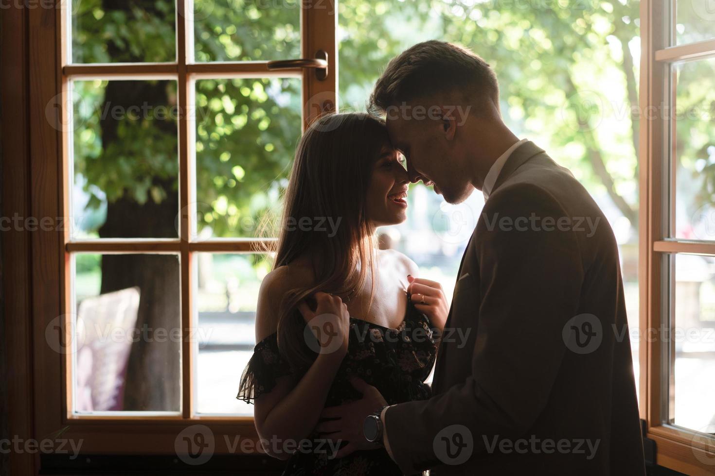 joven pareja enamorada de pie junto a la ventana foto