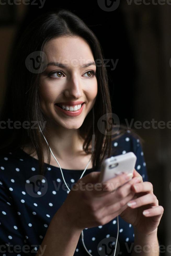 hermosa chica escuchando música en el teléfono con auriculares foto