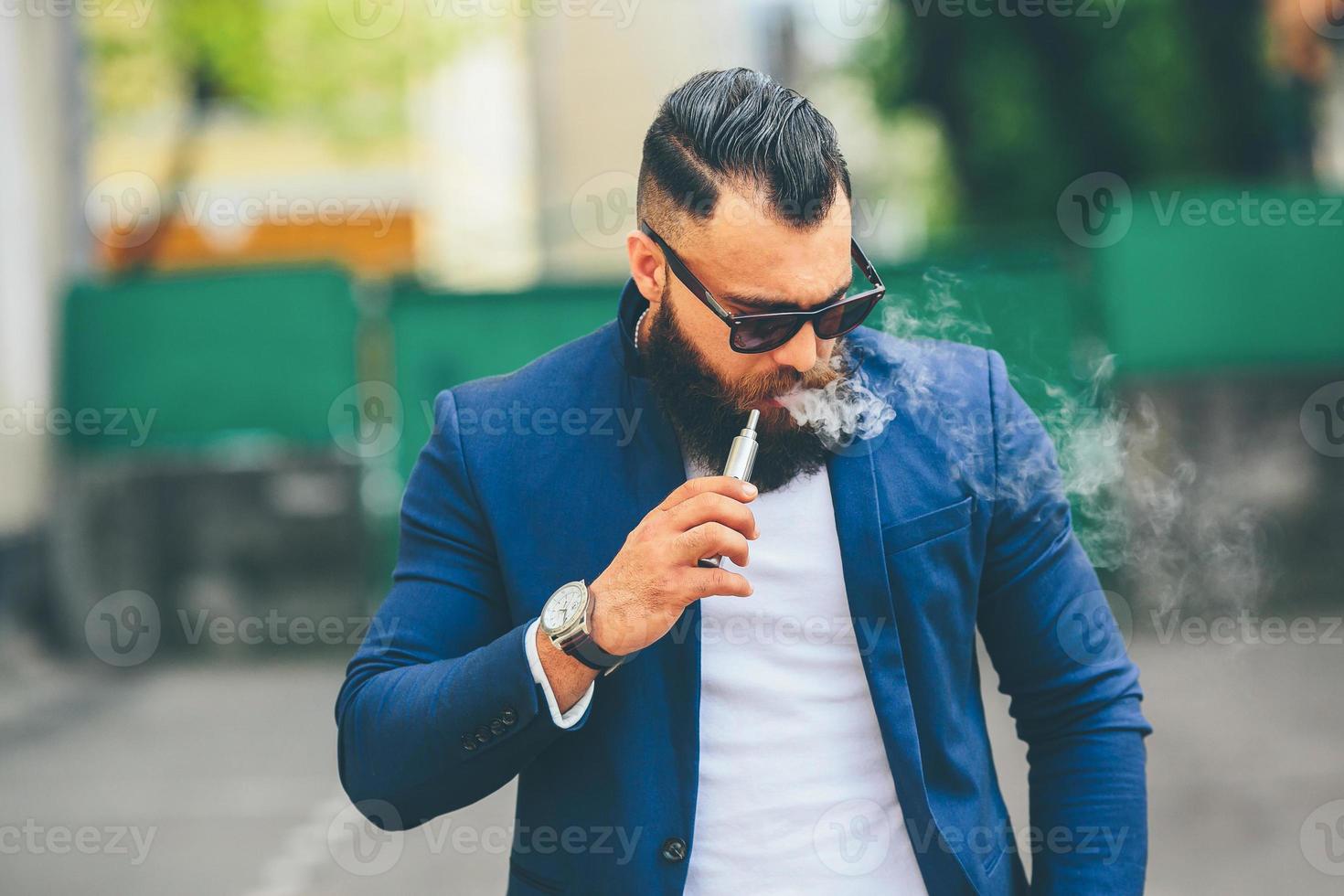 man with a beard smokes electronic cigarette photo