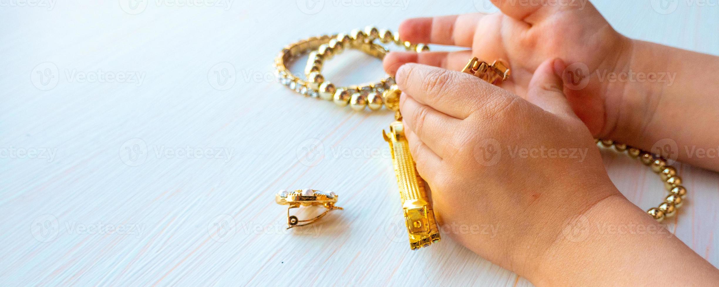 childrens hands play with gold jewelry and bijouterie, on white background. concept of womens happines photo