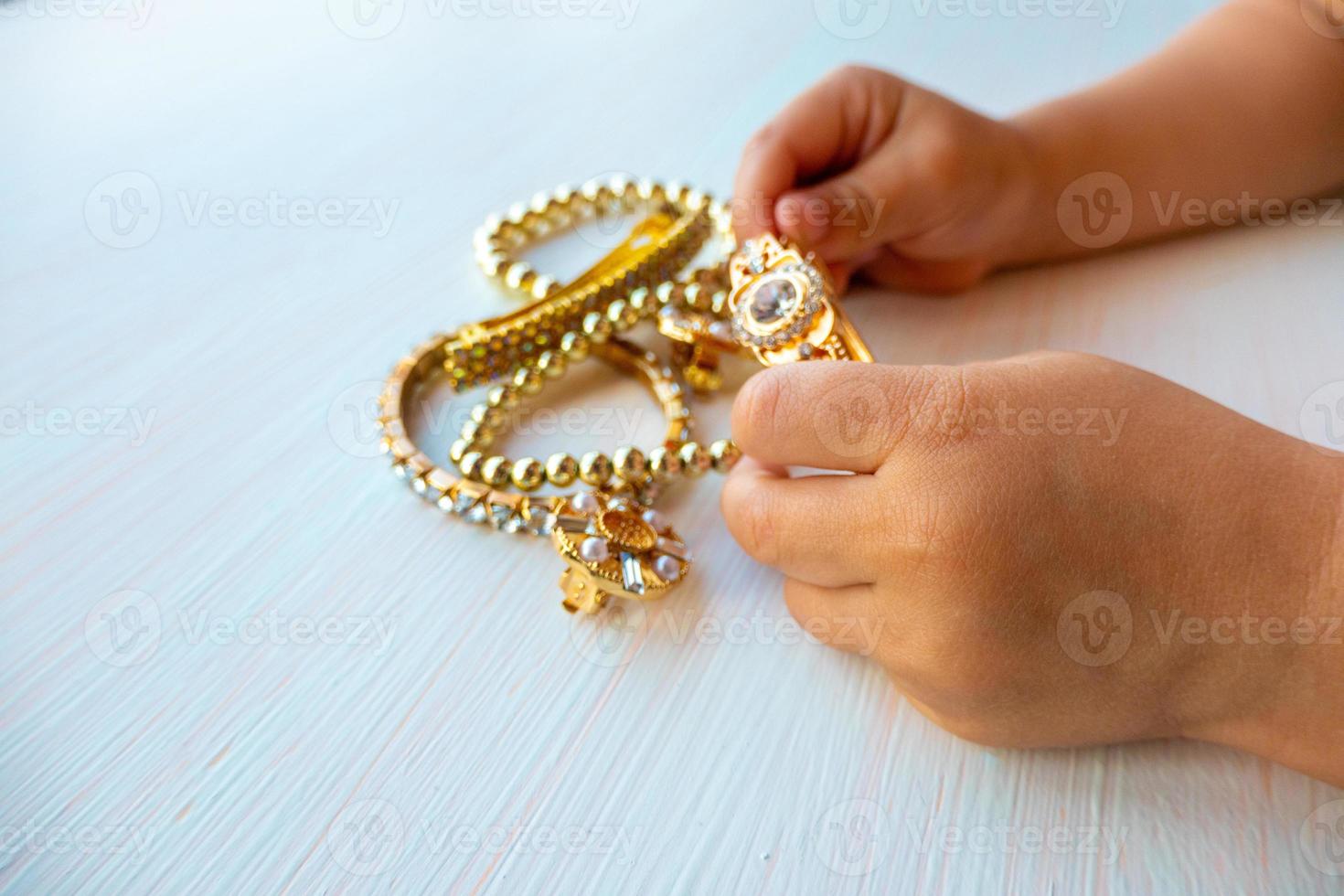 childrens hands play with gold jewelry and bijouterie, on white background. concept of womens happines photo