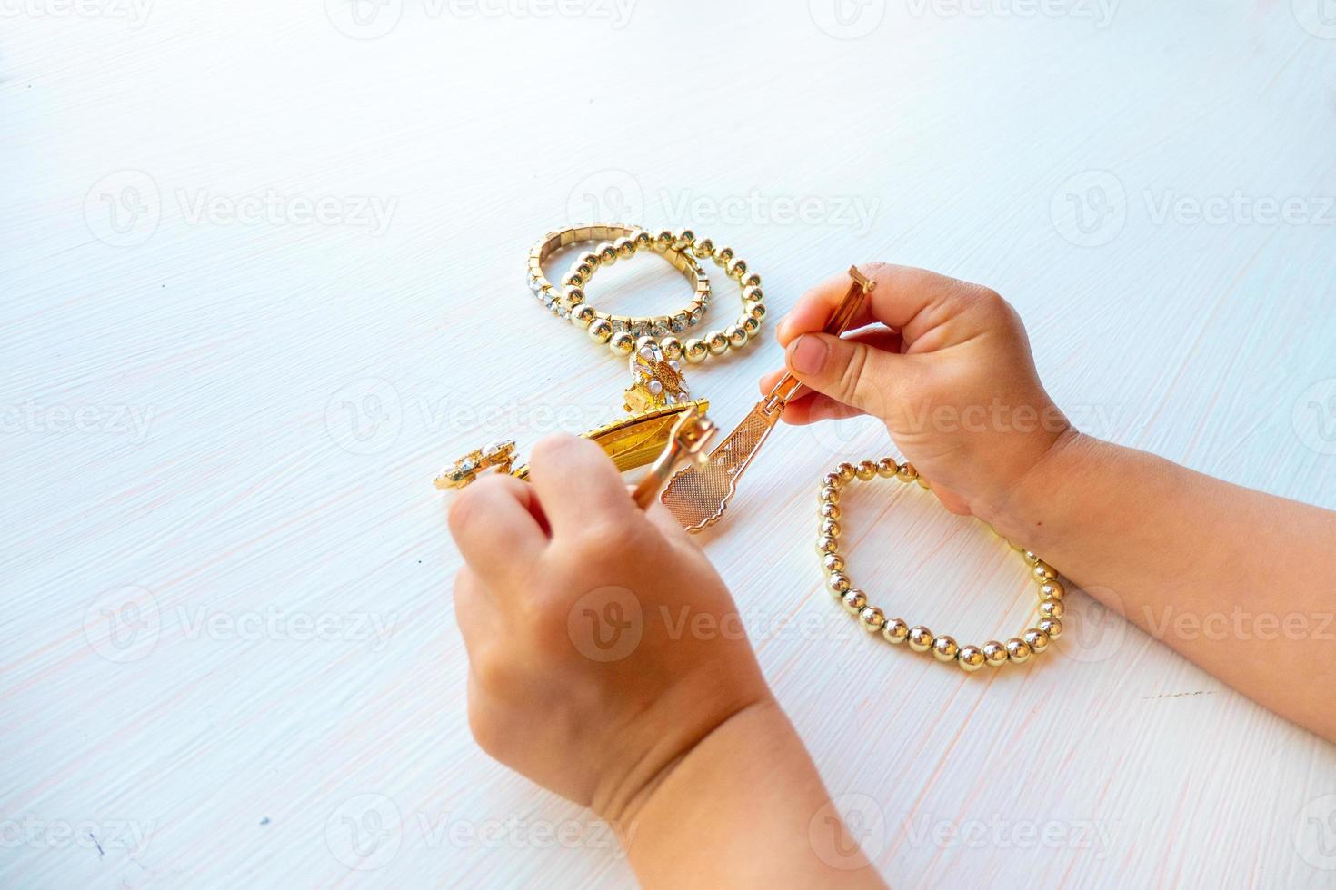 childrens hands play with gold jewelry and bijouterie, on white background. concept of womens happines photo