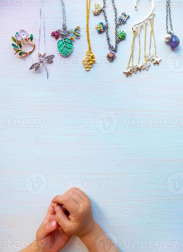 las manos de los niños juegan con bisutería ligera de verano, sobre fondo blanco. concepto de felicidad de las mujeres. copie el espacio foto