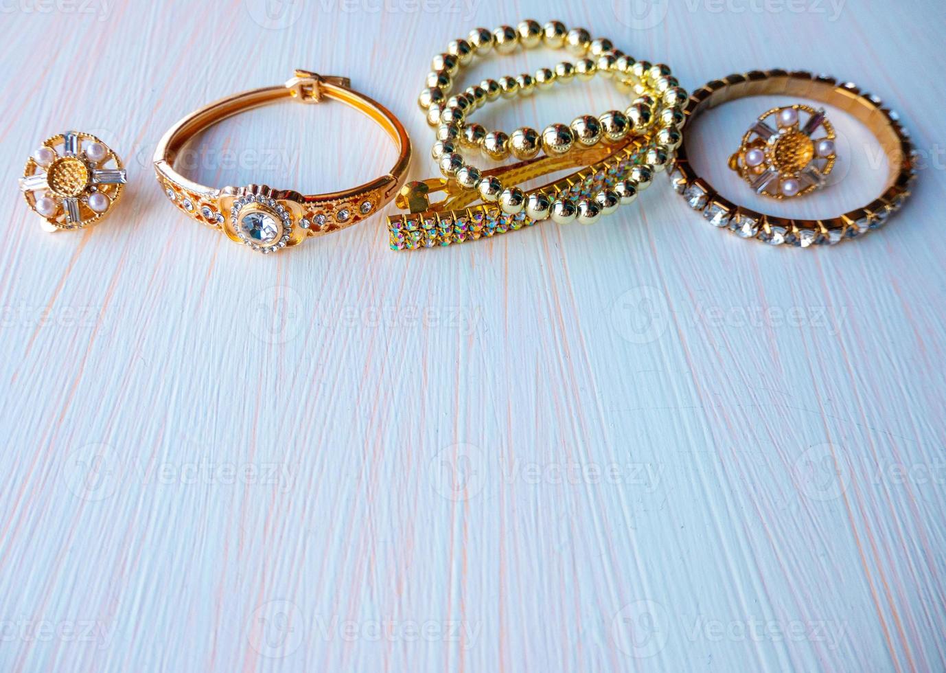 a lot of gold costume jewelry with different materials on a white