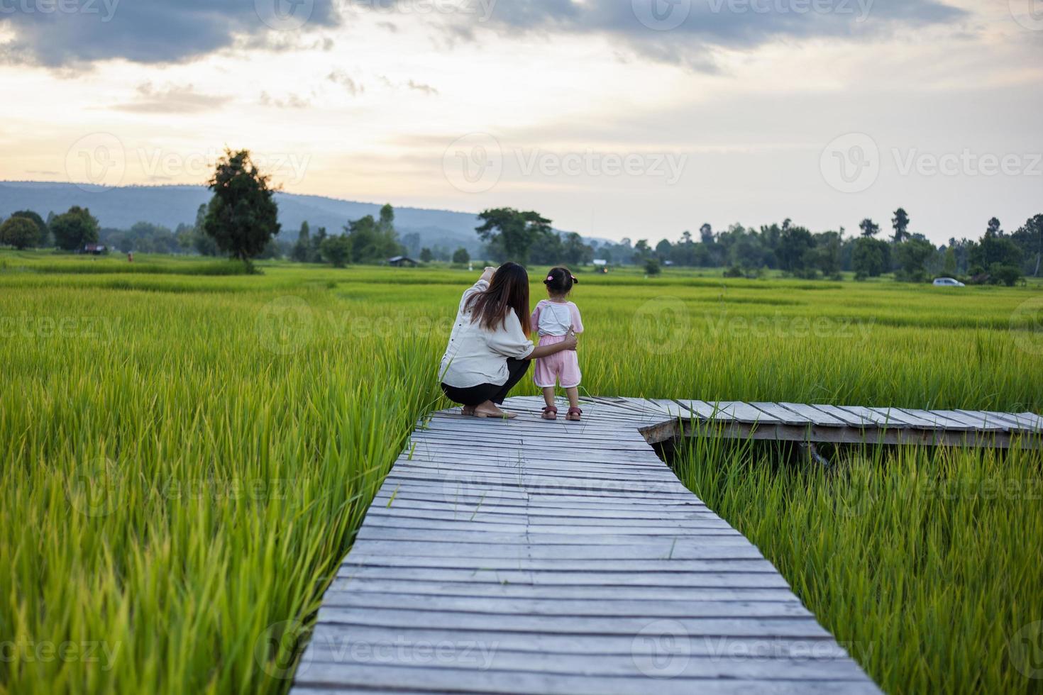 Mother and daughter doing activities together, walking to see the beautiful rice fields and mountains during the sunset time. photo