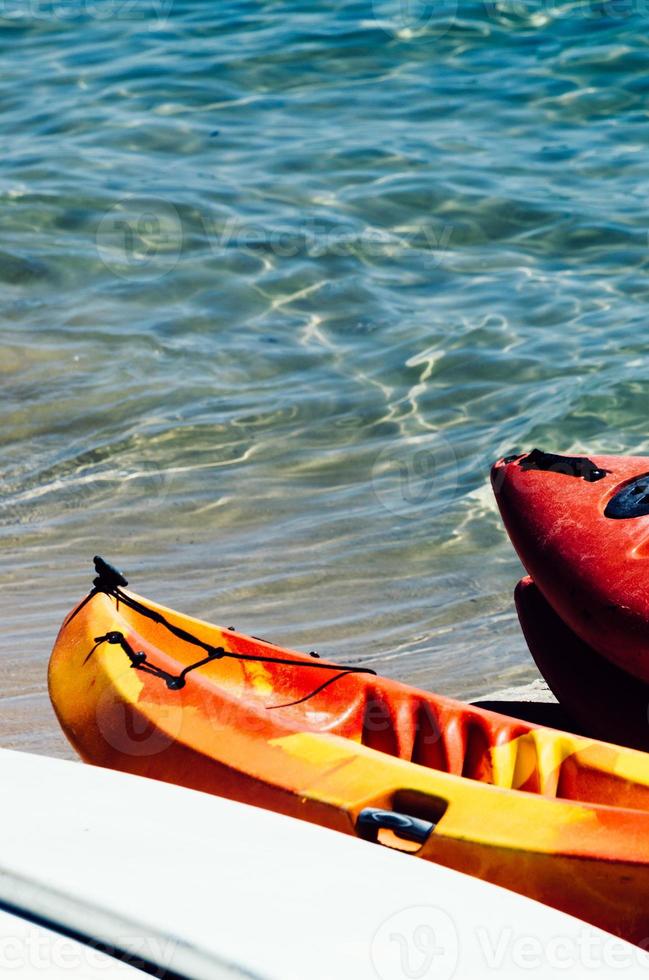 Active rest, sport, kayak. Boat for rafting on water. A few kayaks stand on a sandy beach. photo