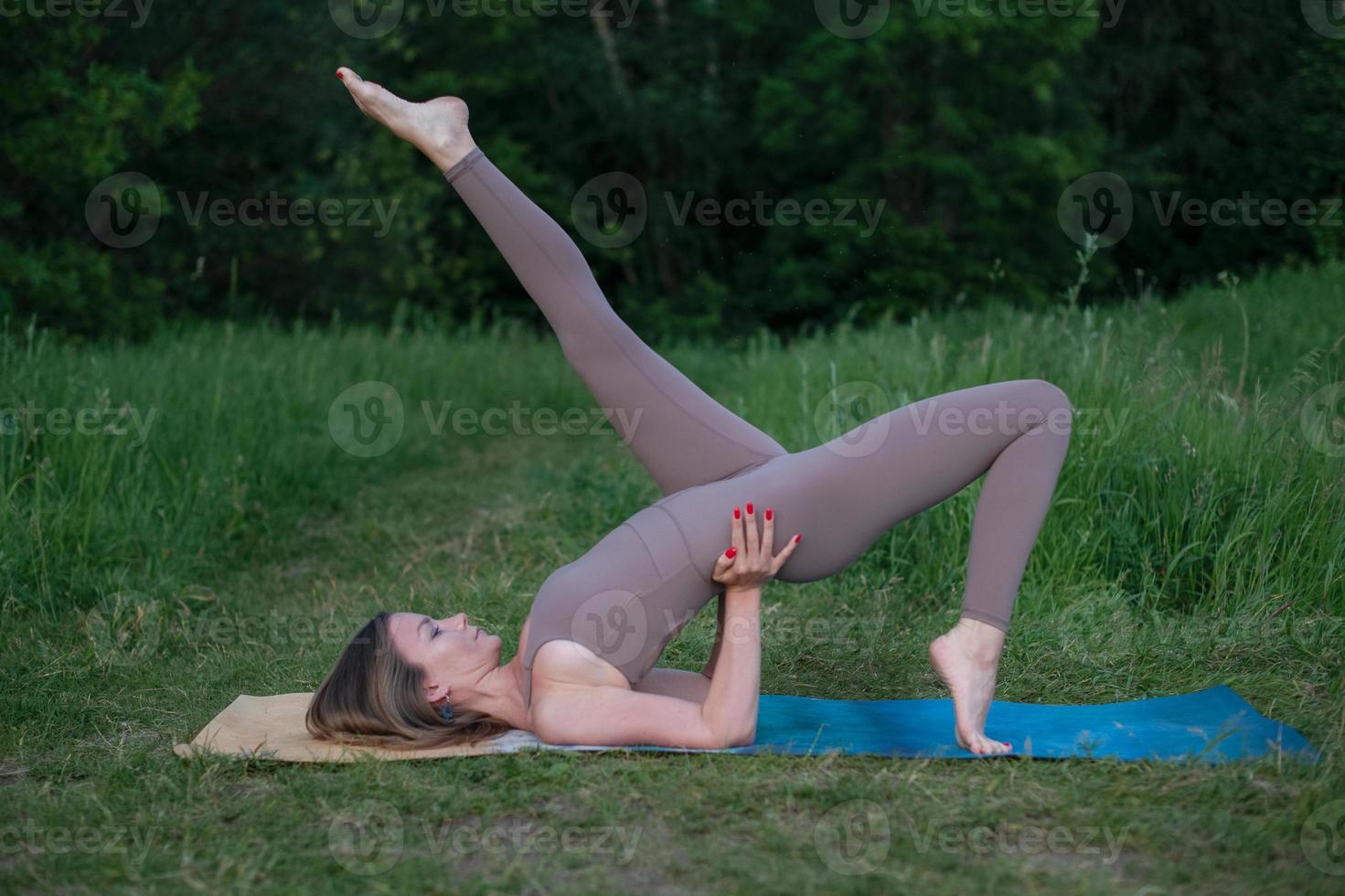 A young gymnast does yoga in nature in the park, using a combination of traditional yoga poses, pilates and gentle dance. Connection with nature. photo