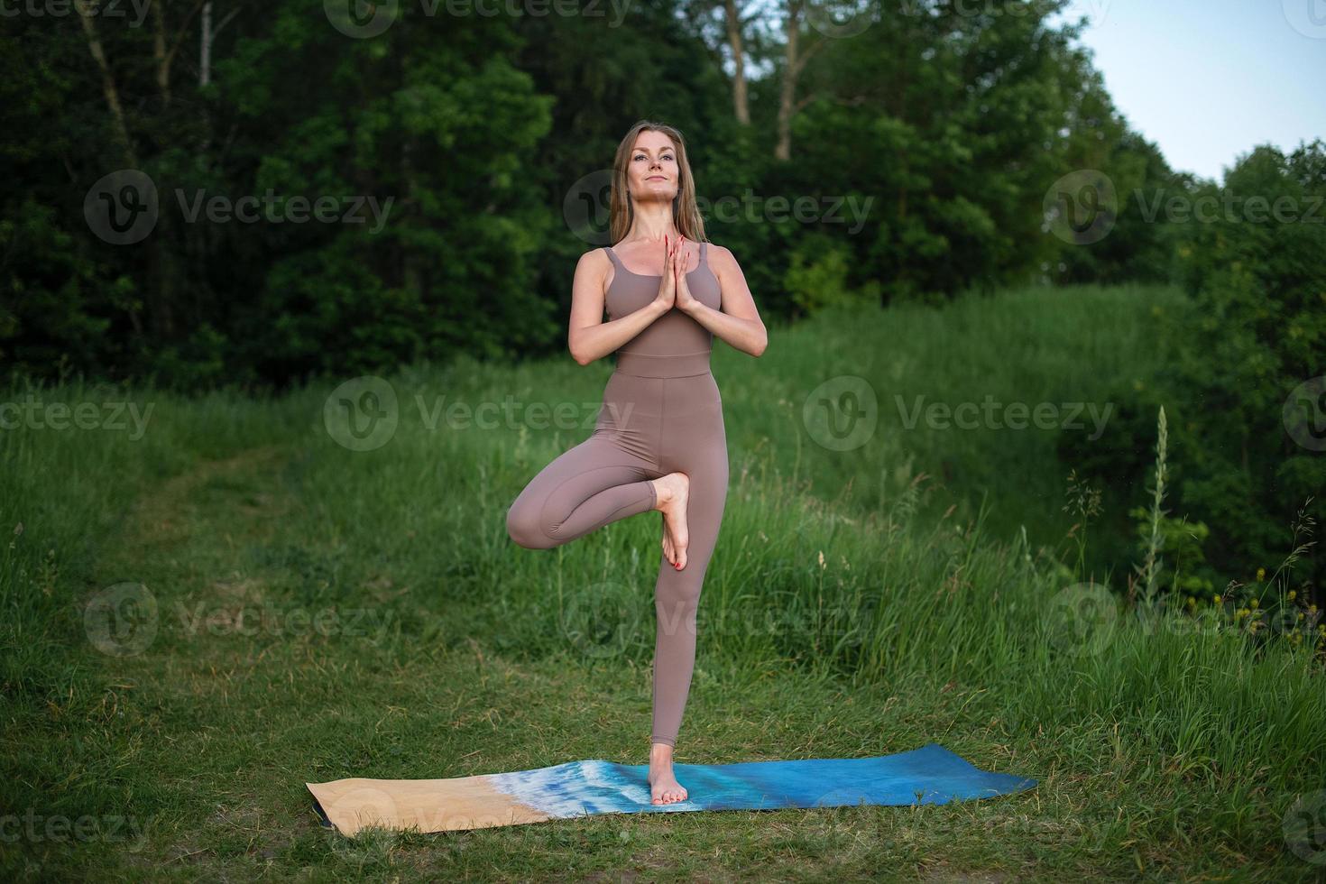 A young gymnast does yoga in nature in the park, using a combination of traditional yoga poses, pilates and gentle dance. Connection with nature. photo