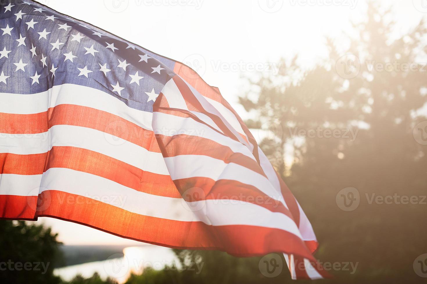 bandera del día de los veteranos de los estados unidos de américa. bandera estadounidense ondeando en el fondo del sol poniente en la naturaleza. foto