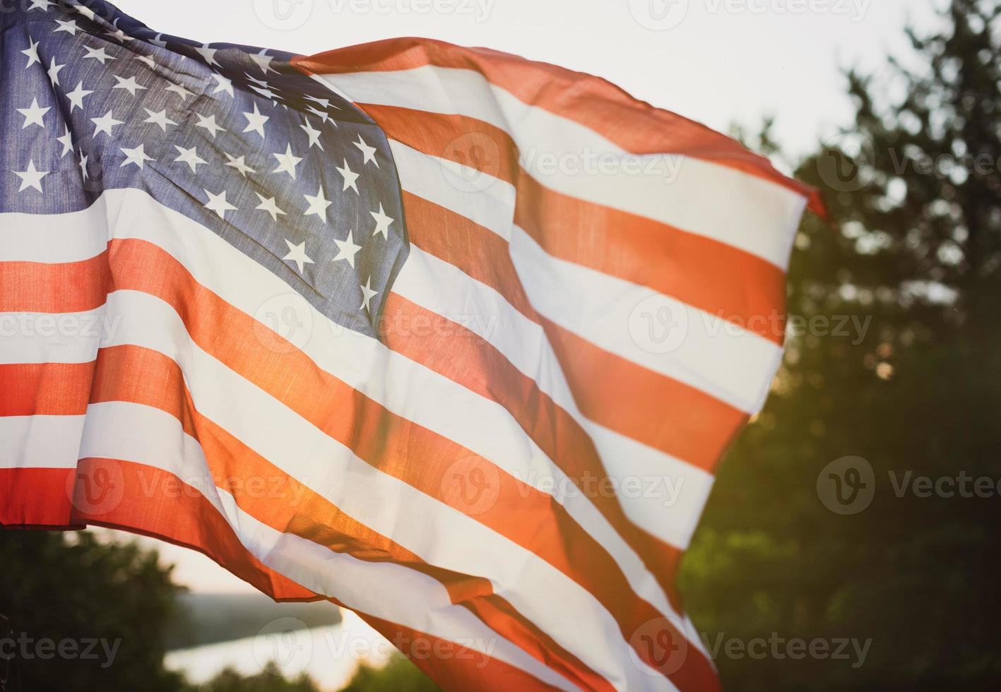 bandera del día de los veteranos de los estados unidos de américa. bandera estadounidense ondeando en el fondo del sol poniente en la naturaleza. foto