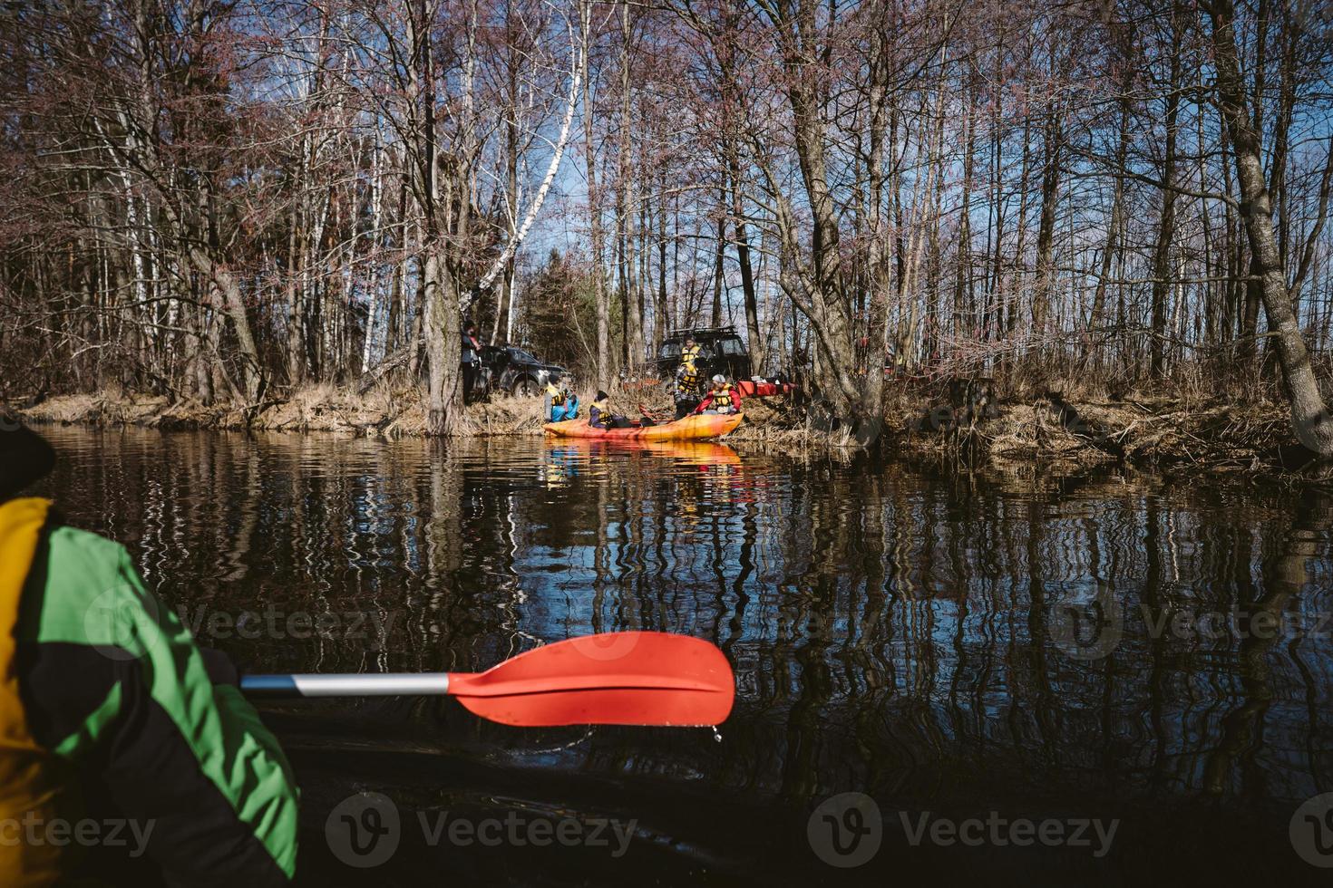 People are kayaking on the river in the forest. photo