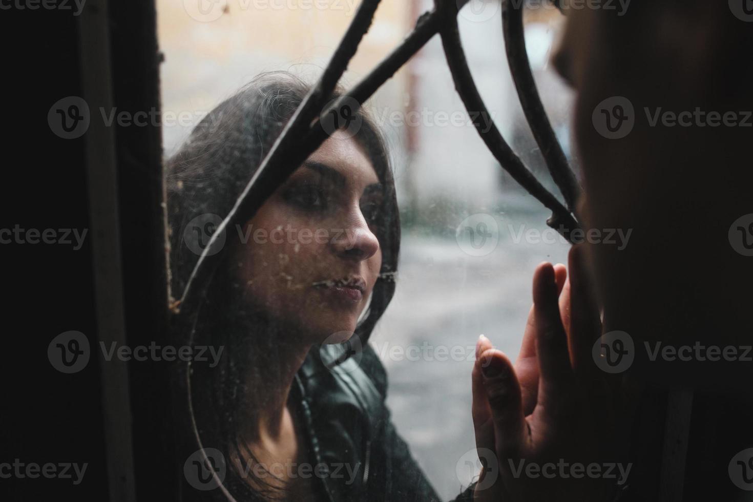 pareja joven europea mirándose a través de la ventana foto