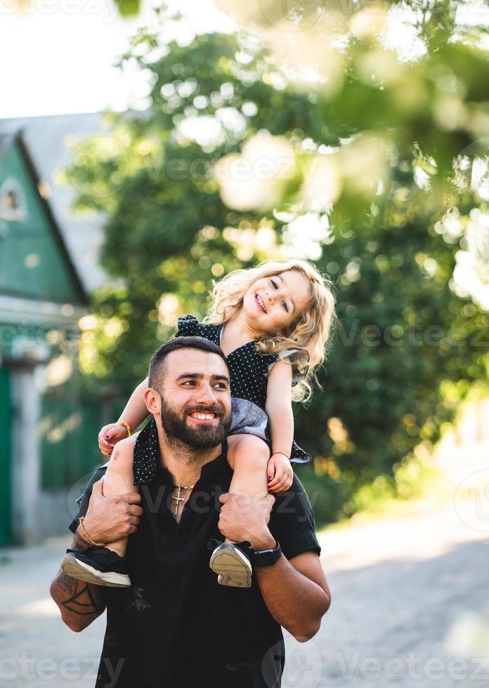 una pequeña hija se sienta en los hombros foto