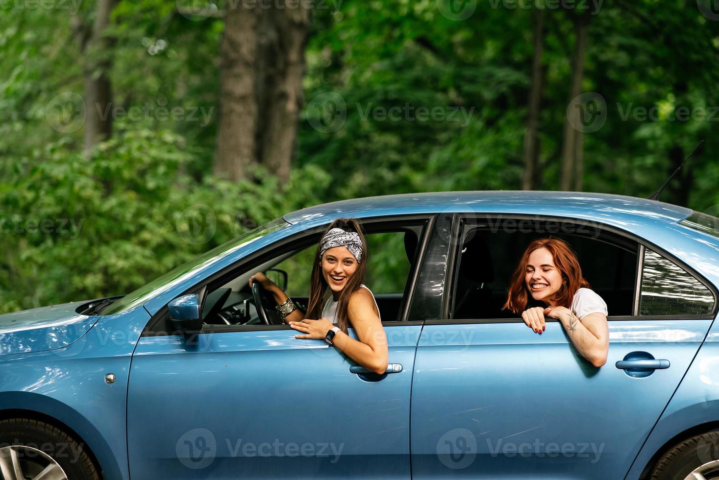 Two girlfriends fool around and laughing together in a car photo