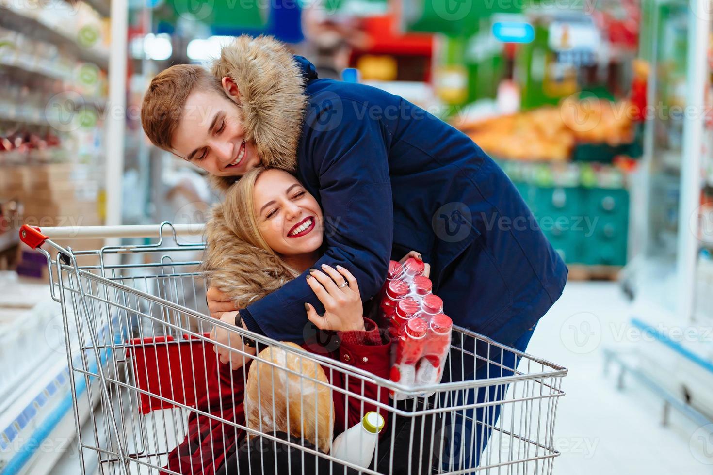 Young handsome guy rides a girl in a supermarket in a trolley photo