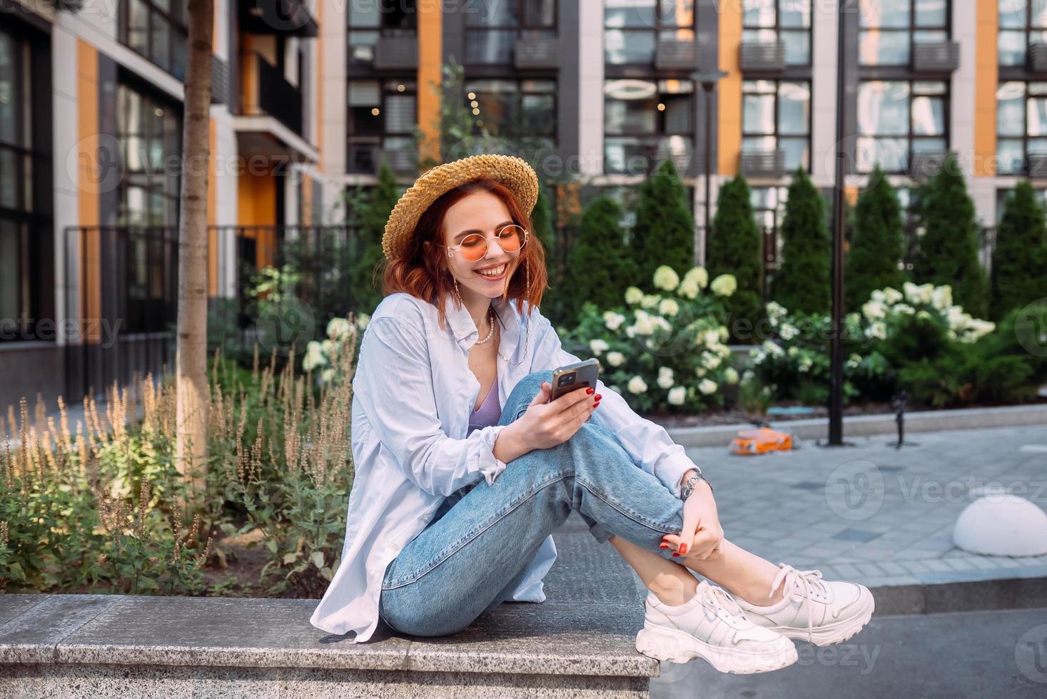 Young lady sitting stairs typing device outside urban city street photo